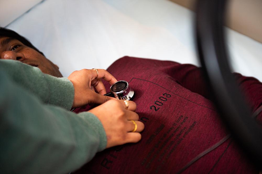 A student is pictured placing a stethoscope on a patient&#039;s chest.