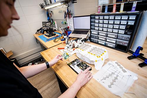 A woman is pictured working on an engineering project at a table.