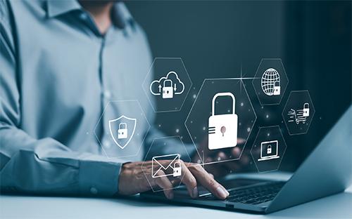 Cybersecurity graphic image with person using laptop (Getty)
