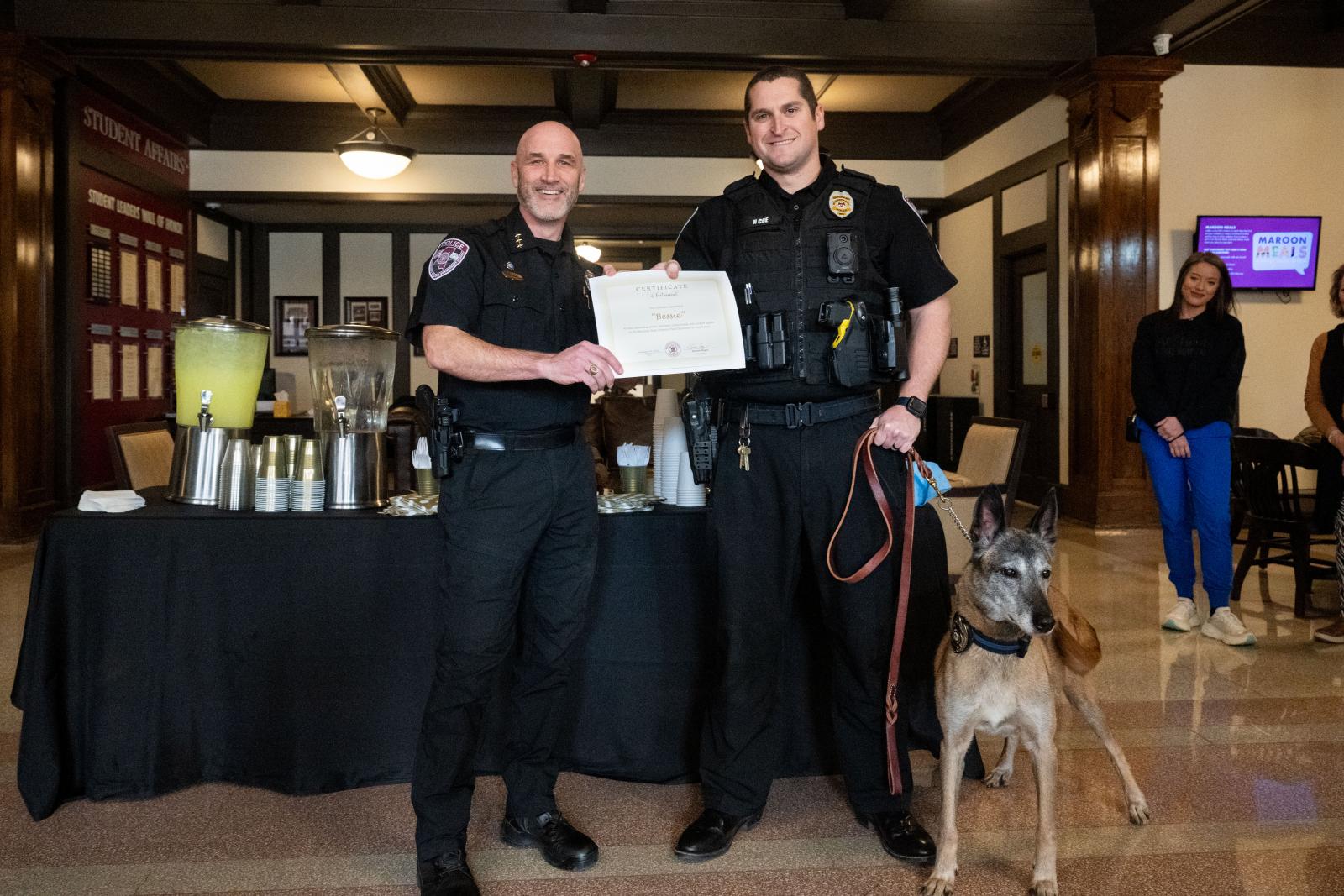 MSUPD celebrates K-9 Bessi’s retirement after nine years of service by presenting her a certificate at a ceremony Jan. 29. Pictured from left, MSU Assistant Police Chief Brian Locke, K-9 Bessi and Sgt. Nick Coe (Photo by Emily Grace McCall)