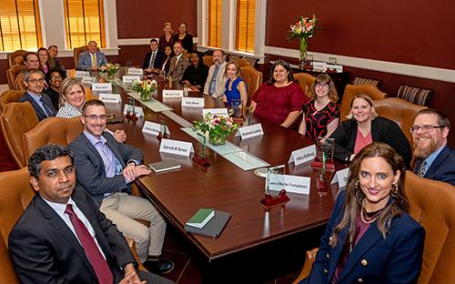Participants of the MSU Faculty Leadership Program pose for a photo while seated at a long table.