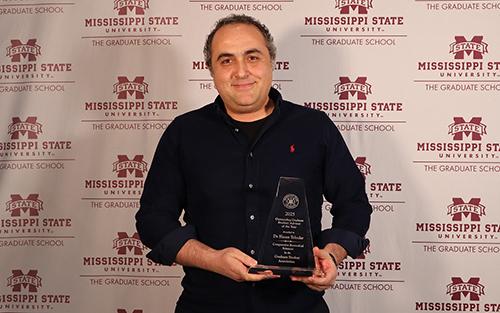 Hasan Tekedar poses with an award.