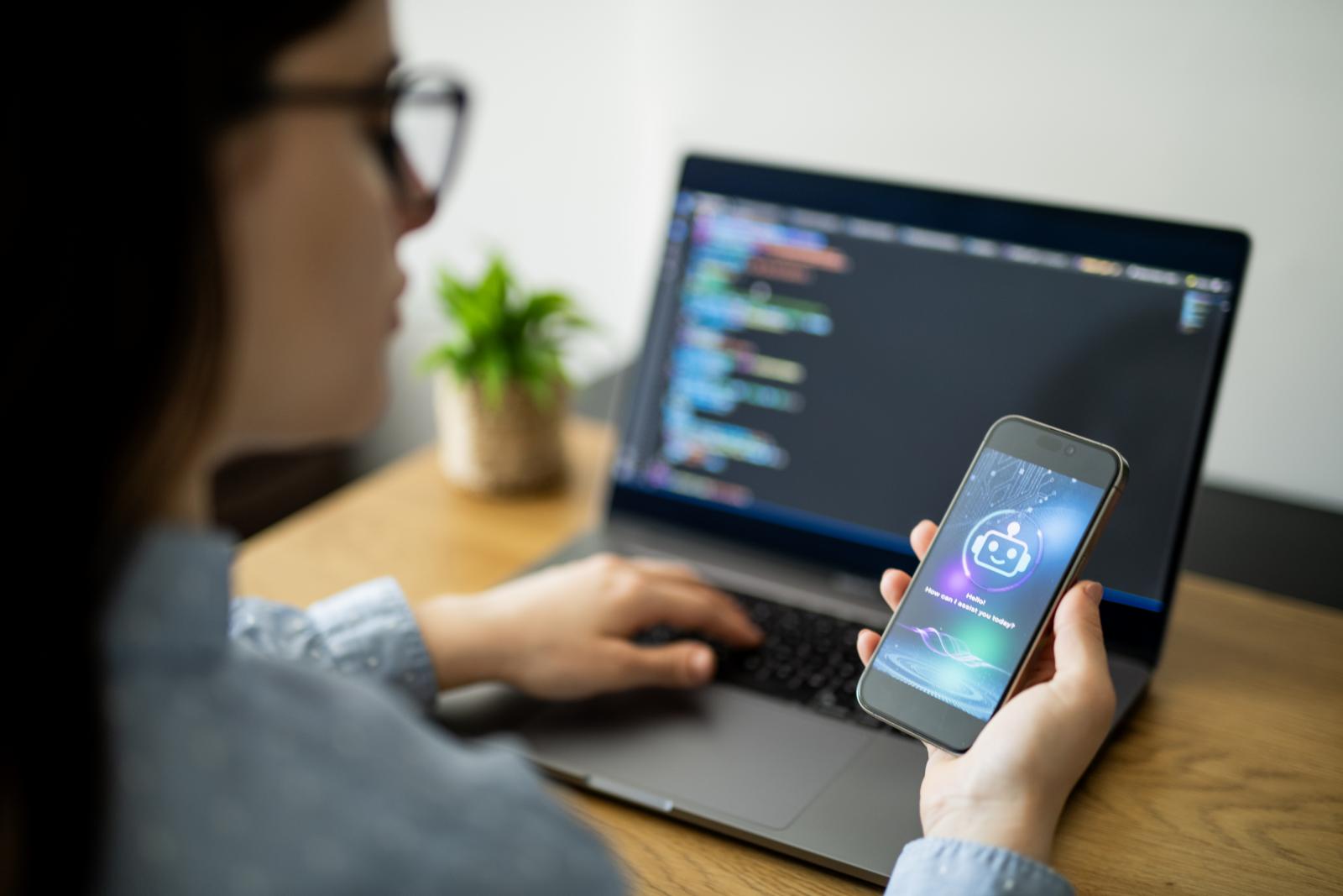 Woman with phone in front of computer