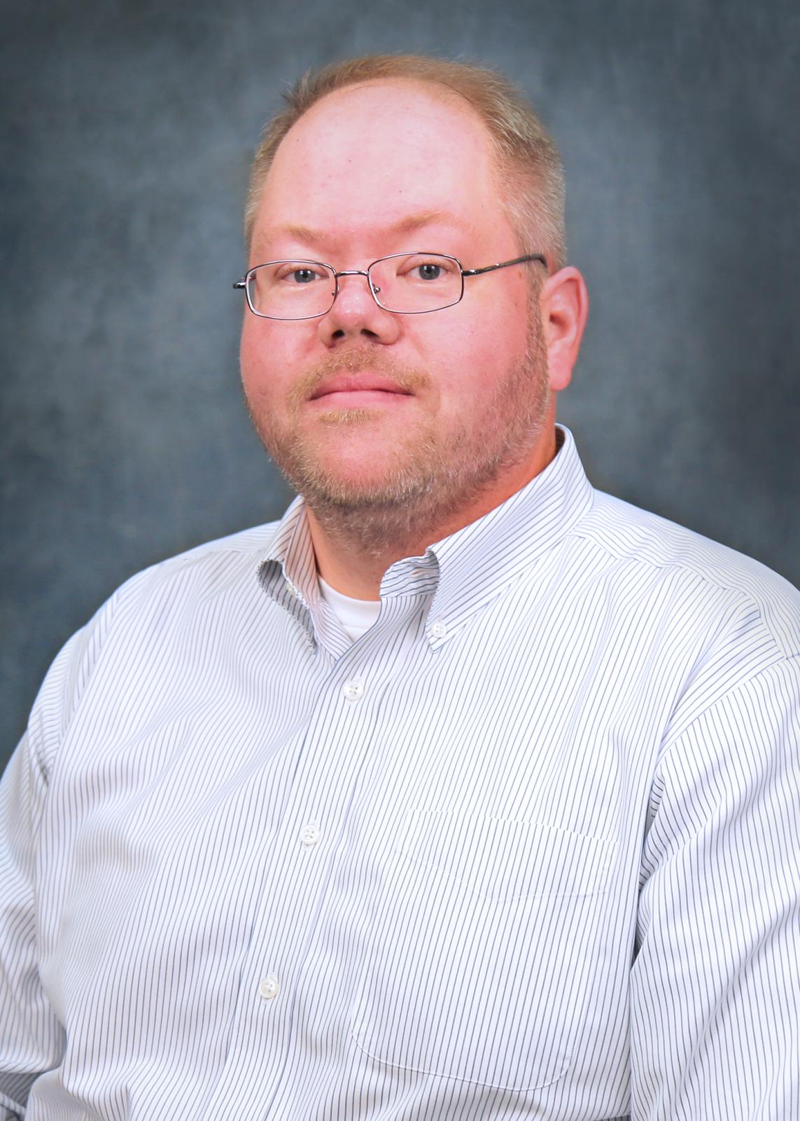 man in light shirt in front of blue background