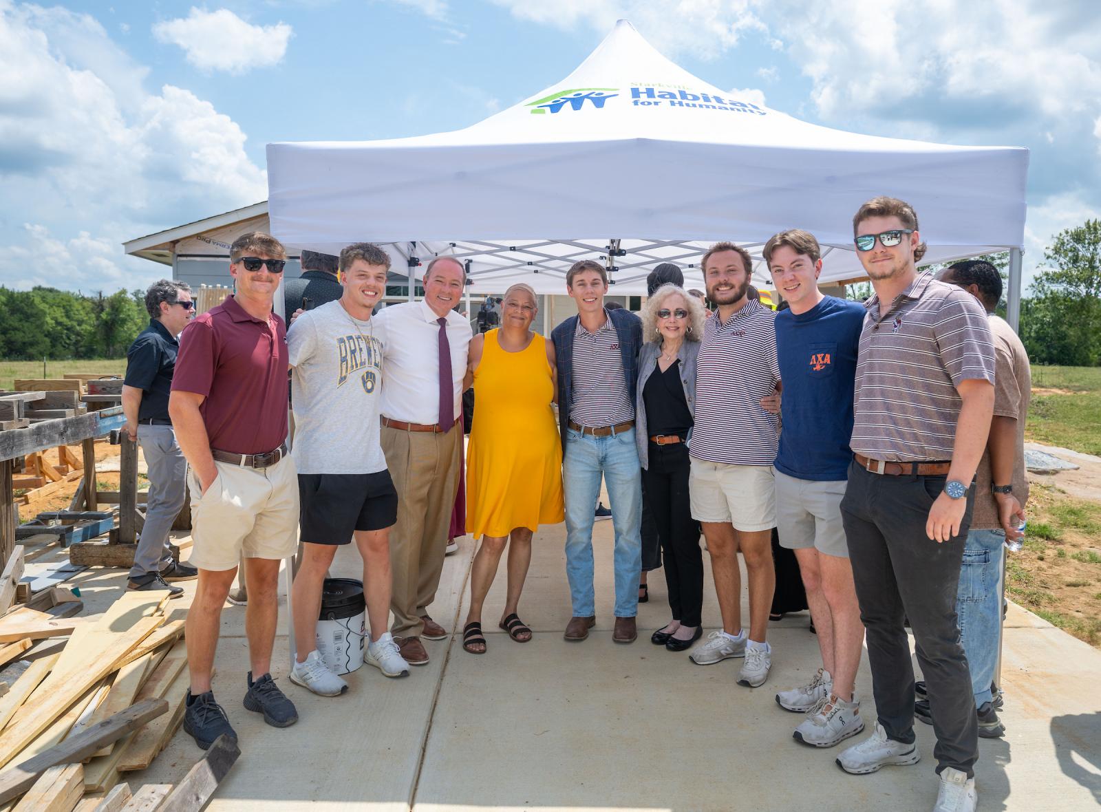 young men  and woman standing in front of a tent