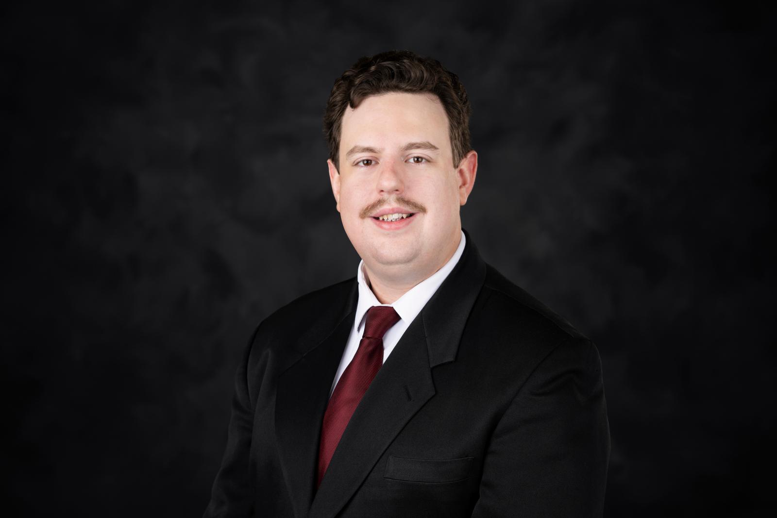 Man in black suit in front of background