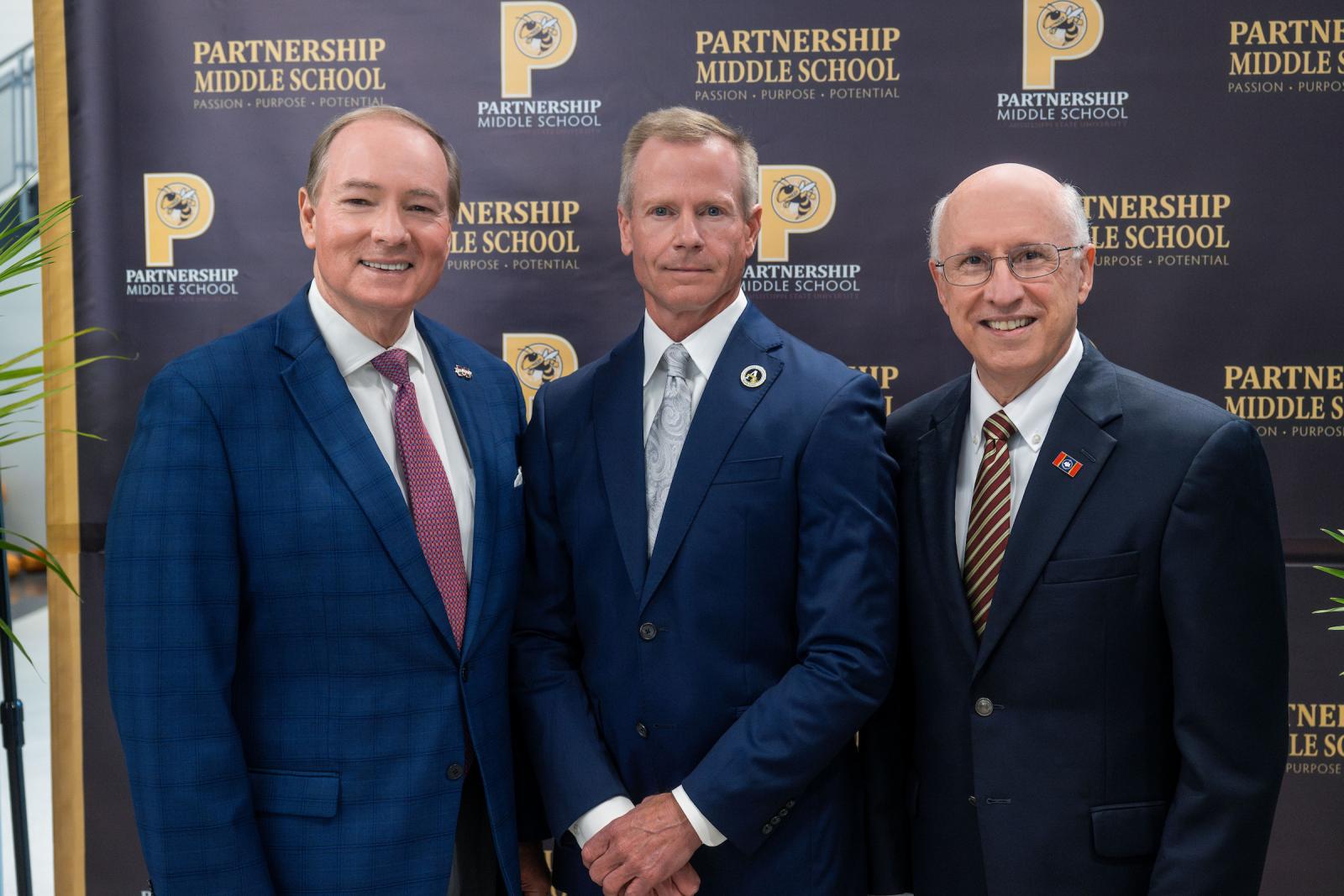 three men in blazers stand