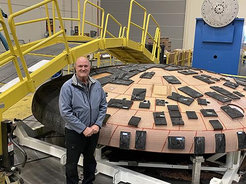 Two-time Mississippi State graduate Terry Abel stands in front of NASA’s Orion Artemis I heat shield, which will protect astronauts during re-entry as part of future deep space missions.