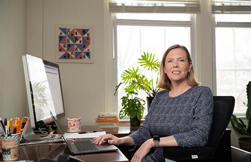 A portrait of Amy Dapper sitting at her desk in her office.