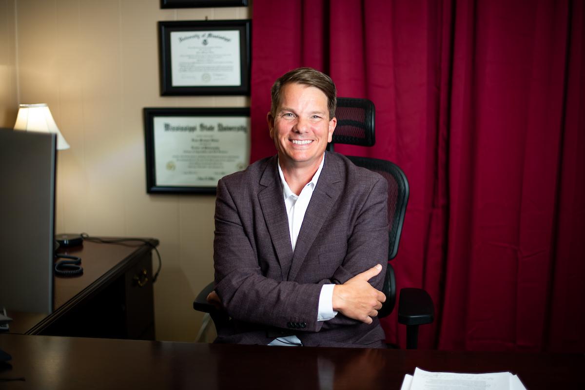 man in jacket in front of diploma