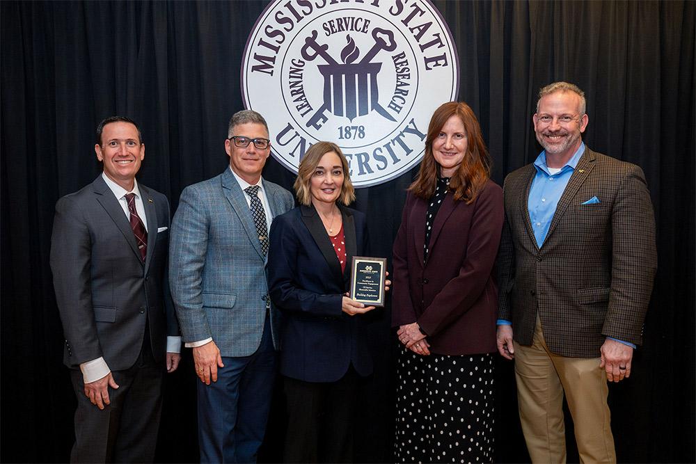 Associate Professor Kelly Moser, Department of Classical and Modern Languages and Literatures, and Professor and Head Kenneth Anthony, Department of Teacher Education and Leadership, center, accept a Community Engagement Award for their Bulldog Explorers Program from Interim Executive Director for Outreach and Engagement Joe Fratesi, left, and Associate Vice President for the Division of Agriculture, Forestry and Veterinary Medicine Ashli Brown and Senior Vice Provost Brent Fountain, right.