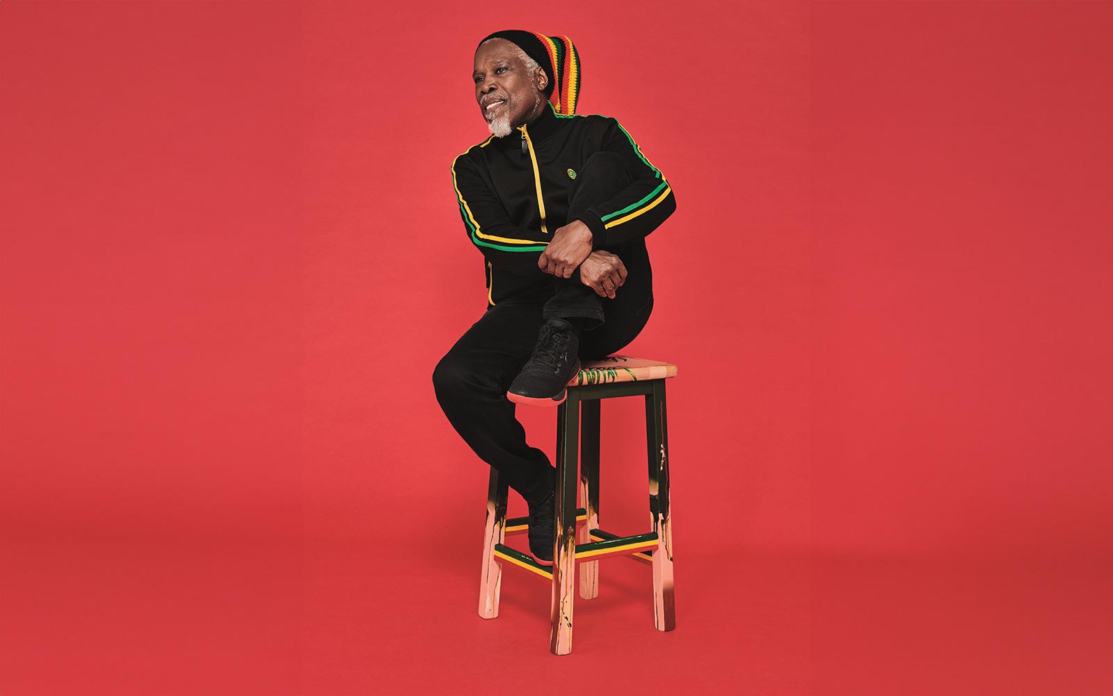 man sitting on wooden stool on red background