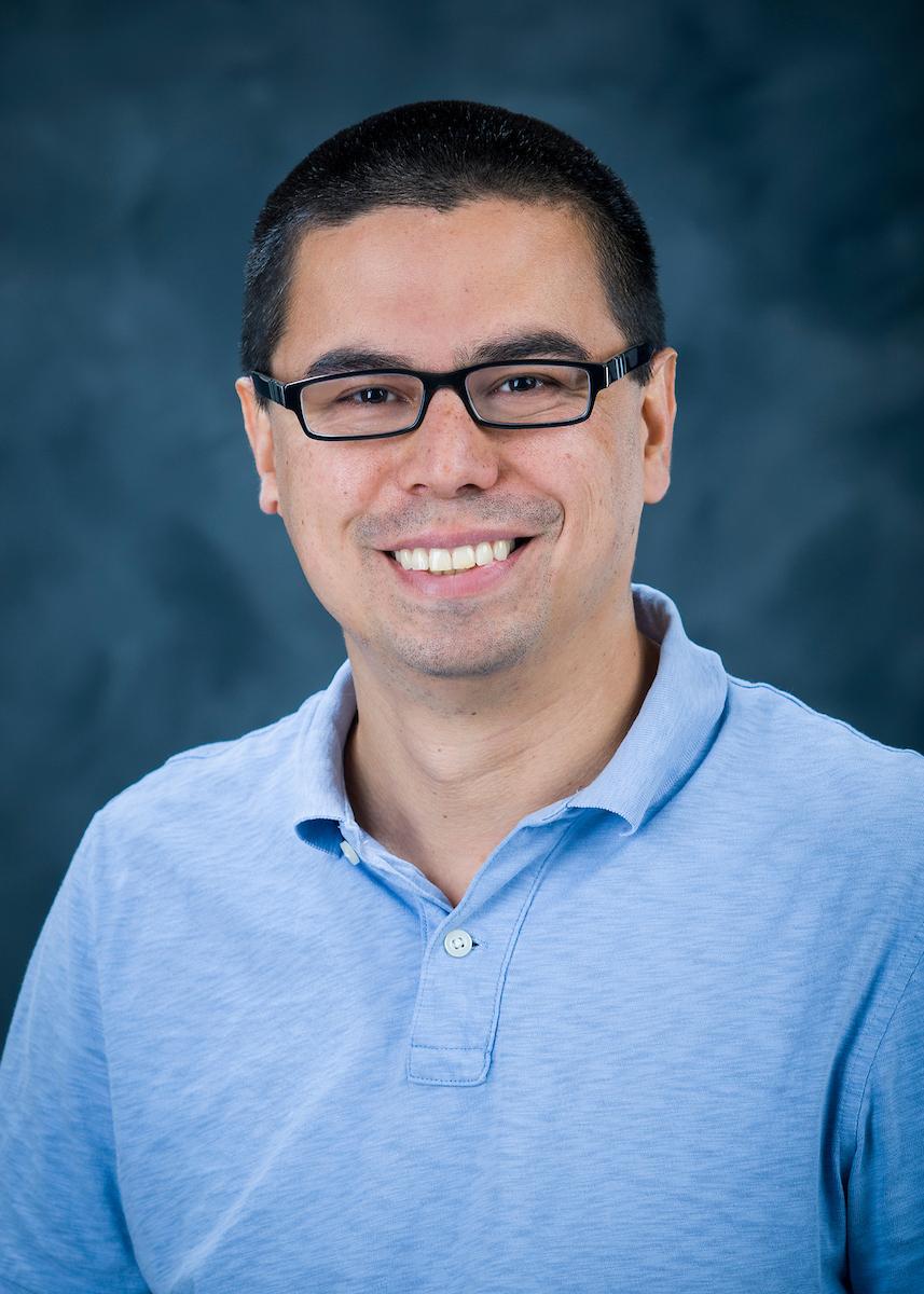 Headshot of Gabitov in a blue polo on a blue background