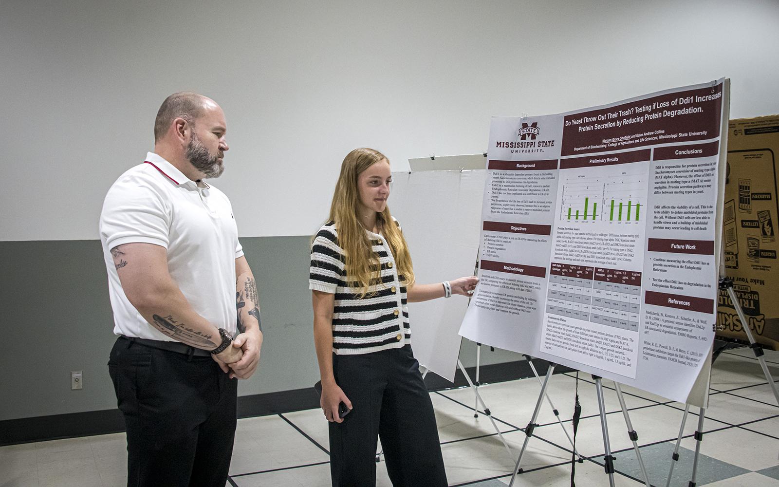 Andrew Williams, food science, nutrition and health promotion master’s student looks over the poster of Morgan Grace Sheffield, a senior biochemistry major, at the Mississippi Academy of Sciences Summer Science and Engineering Symposium.