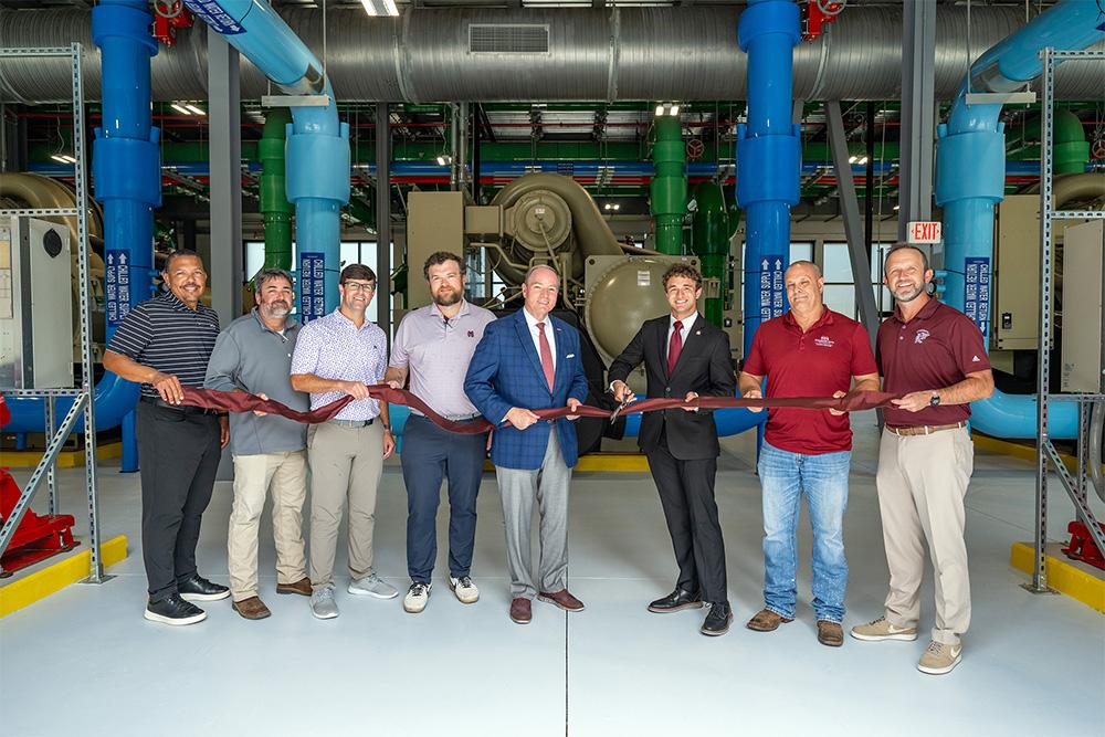 A group of men cut a ribbon in front of equipment at MSU's new state-of-the-art mechanical plant.